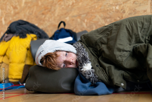 Ukrainian teenage boy war refugee in temporary shelter and help center. photo