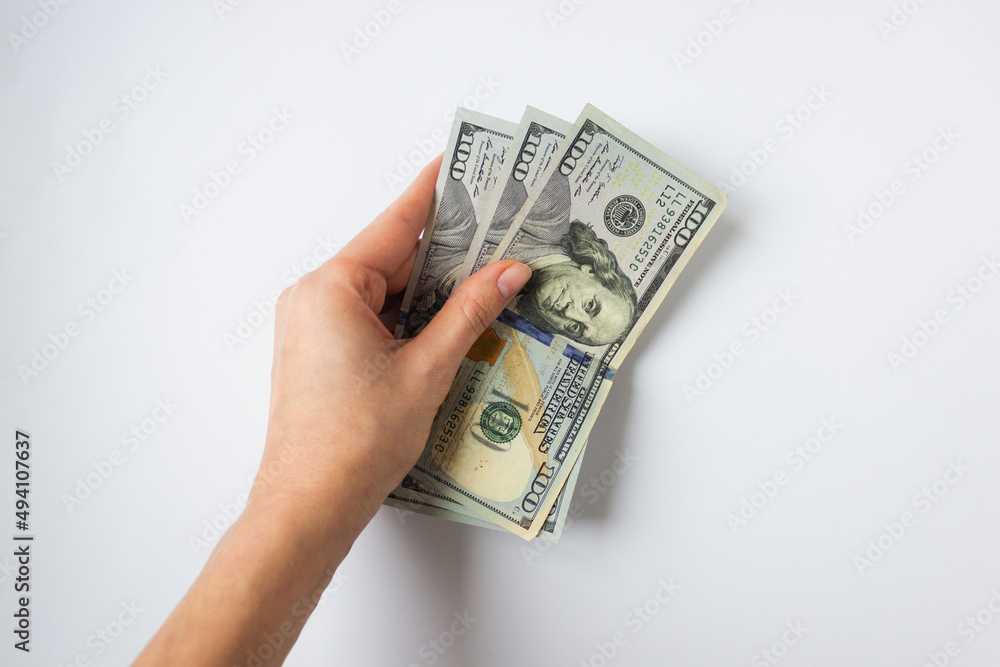 Woman's hand holds money 300 dollars for immigration on white background. Because of the war and Russian aggression. Woman's hand holds money 300 dollars for immigration on white background. Because of the war and Russian aggression.