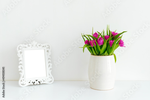 Fototapeta Naklejka Na Ścianę i Meble -  A bouquet of purple tulips in a white vase on a table
