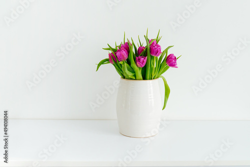 Bouquet of purple tulips in a vase on a white background