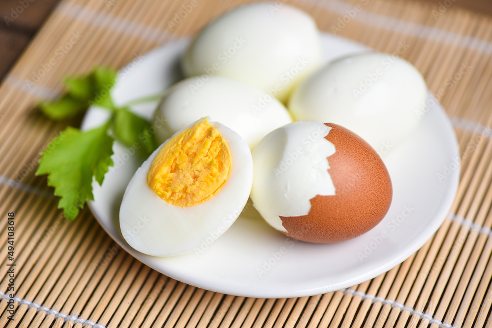 Egg cooking healthy eating concept, Eggs breakfast, fresh peeled eggs menu food boiled eggs and eggshell on white plate decorated with leaves green celery on wooden background