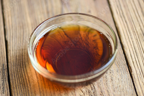fish sauce on glass bowl and wooden background, fish sauce obtained from fermentation fish or small aquatic animal, fermented foods