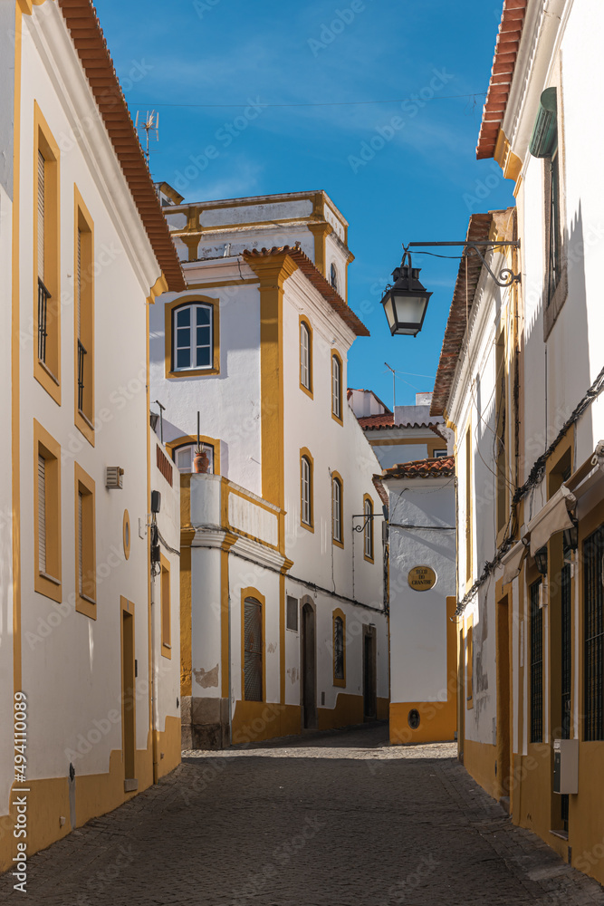 The view of narrow paved street of Evora with the cozy white houses. Evora. Alentejo. Portugal