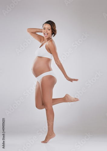 My bodys changed and I love it. Studio portrait of a beautiful young pregnant woman posing against a gray background.