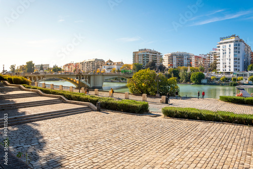 A sunny autumn day along the Guadalquivier River in the Historic Center of Seville, Spain with the Puente de San Telmo bridge in view..