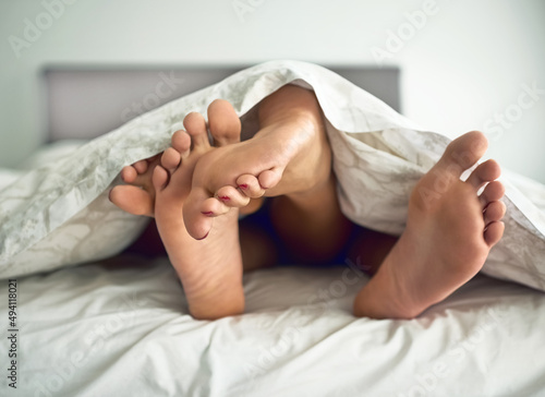 Frisky feet. Shot of a couples feet poking out from under the bed sheets.
