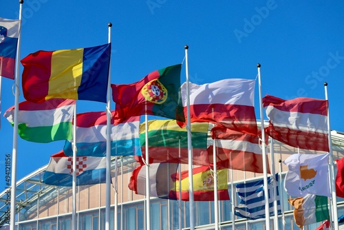 Group of EU memberstate flags waving in wind by EIB building in Luxembourg: Romania, Portugal, Poland, Austria, Hungary, Luxembourg, Lithuania, Latvia, Cyprus, Croatia, and Spain