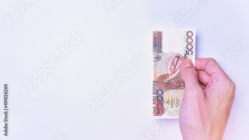 Indonesian Rupiah the official currency of Indonesia. Man's hand is making a payment. Male hand showing Indonesian Rupiah Note. Business Investment Economy and Finance Concept Uang 5000 5.000 Rupiah