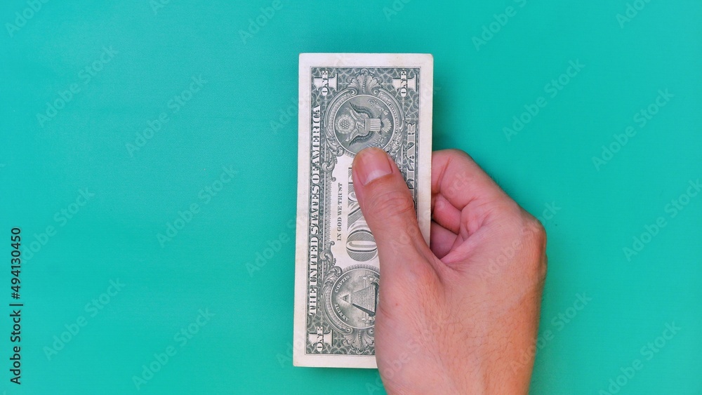 Man's hand is making a payment. Business Investment Economy Money Loan Saving and Finance concept. Male hand showing Dollar bills on green background. One Dollar. 1 USD. Prosperity concept. Man's hand is making a payment. Business Investment Economy Money Loan Saving and Finance concept. Male hand showing Dollar bills on green background. One Dollar. 1 USD. Prosperity concept.