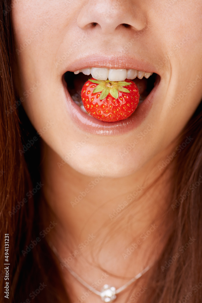 Delectable fruit. Cropped image of a woman with a strawberry in her mouth. Delectable fruit. Cropped image of a woman with a strawberry in her mouth.