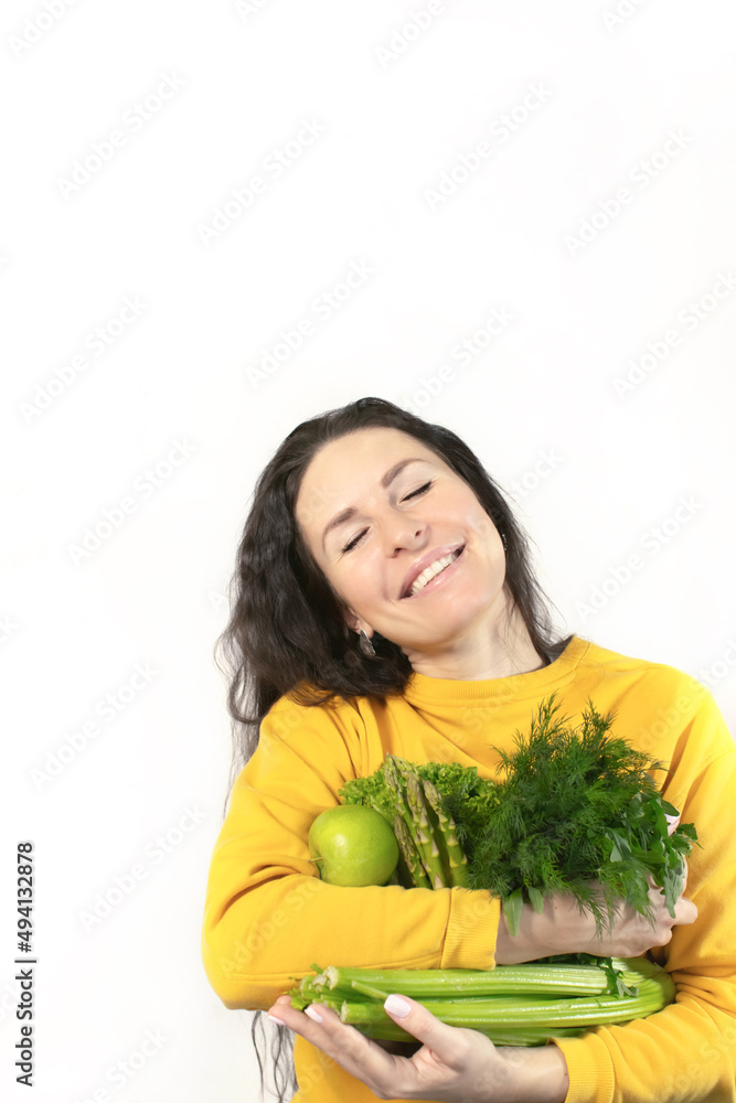 Smiling woman with apples, celery and dill with parsley. Spring and vitamins. The concept of healthy nutrition. Front photo. Smiling woman with apples, celery and dill with parsley. Spring and vitamins. The concept of healthy nutrition. Front photo.