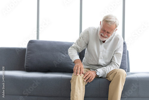 Fotografie senior man suffering from knee ache on sofa
