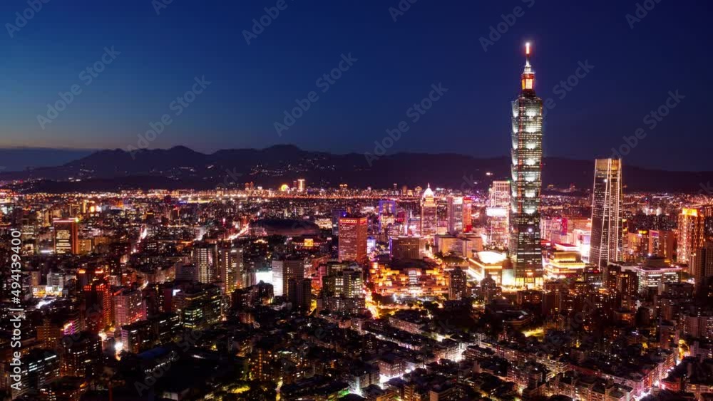 Aerial hyperlapse of Downtown Taipei at dusk, vibrant capital city of Taiwan, with 101 Tower standing out amid skyscrapers in XinYi Commercial District and city lights dazzling under blue twilight sky Aerial hyperlapse of Downtown Taipei at dusk, vibrant capital city of Taiwan, with 101 Tower standing out amid skyscrapers in XinYi Commercial District and city lights dazzling under blue twilight sky
