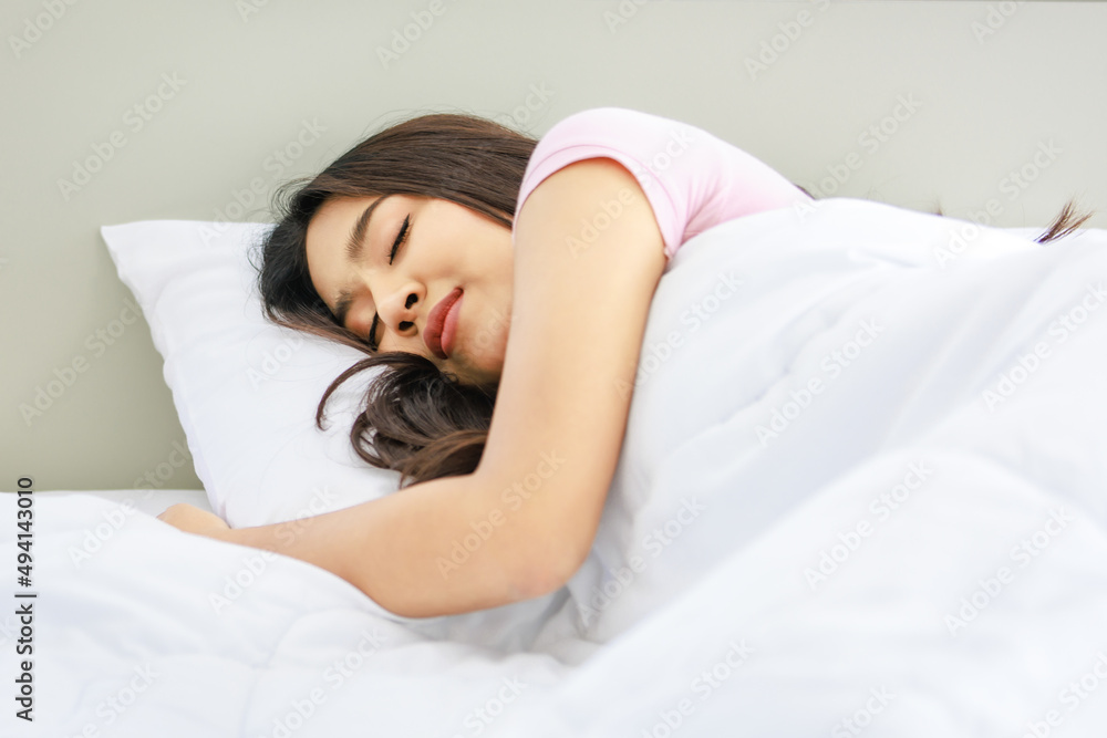 Asian young beautiful happy lazy sleepy female teenager model in casual pajama outfit in morning sleeping alone smiling under white blanket on bed in bedroom Asian young beautiful happy lazy sleepy female teenager model in casual pajama outfit in morning sleeping alone smiling under white blanket on bed in bedroom