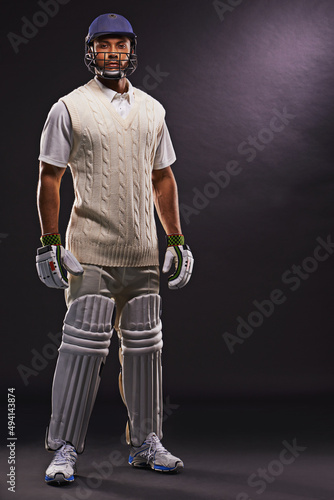 Ready to hit the pitch. A cropped shot of an ethnic young man in cricket attire isolated on black. photo