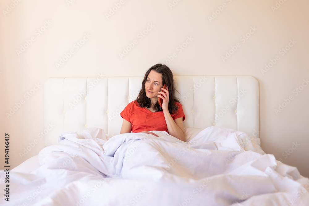 A woman sits on a bed and calling on the phone A woman sits on a bed and calling on the phone