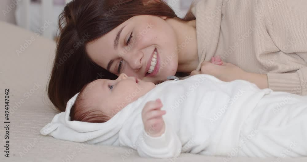Maternal love. Caring mother smiles at newborn baby Maternal love. Caring mother smiles at newborn baby