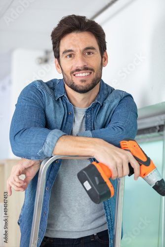 man on stepladder holding a cordless drill
