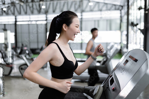exercise concept The female exercise club member enjoying running on treadmill and having interaction with the male member running next to her