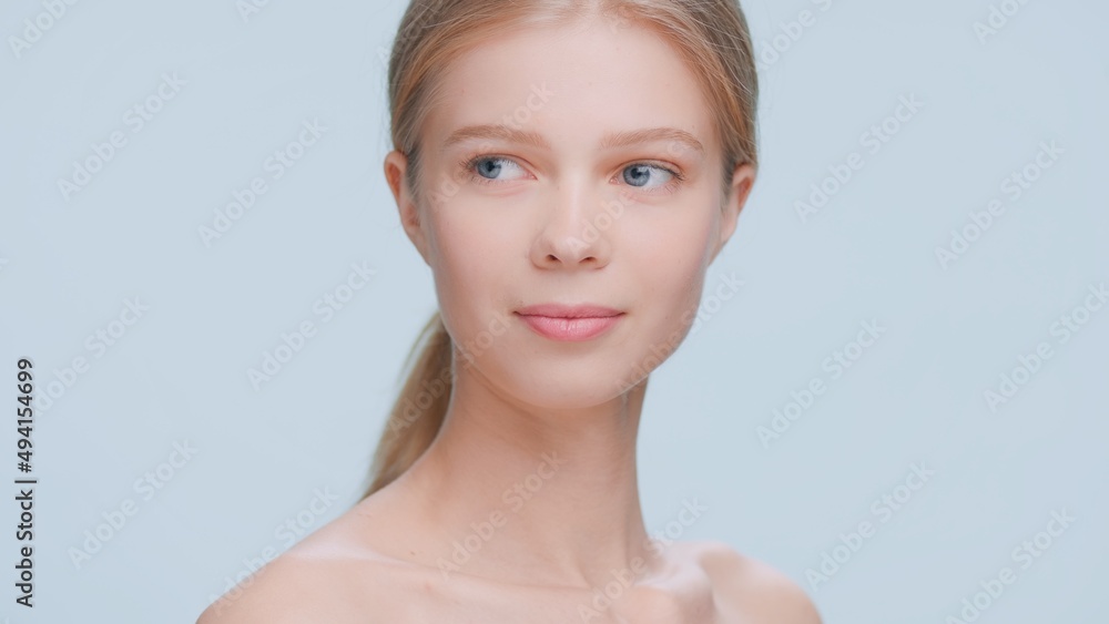 Young attractive blonde beauty model looks aside on blue background | Skin care commercial concept Young attractive blonde beauty model looks aside on blue background | Skin care commercial concept