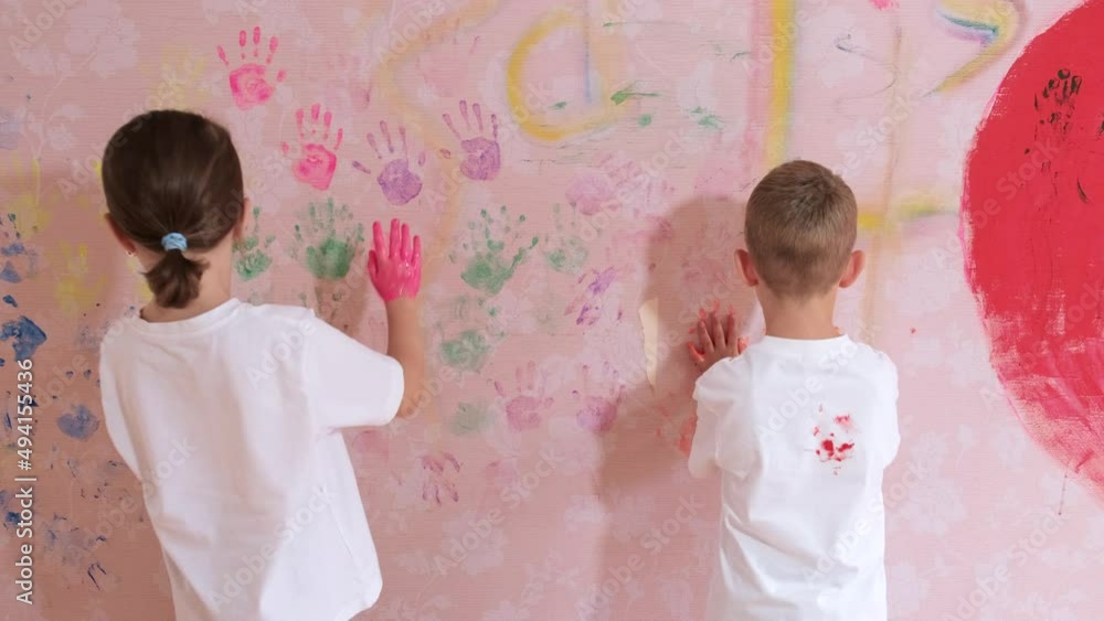 A little boy and girl drawing with palms and paints on the pink ...