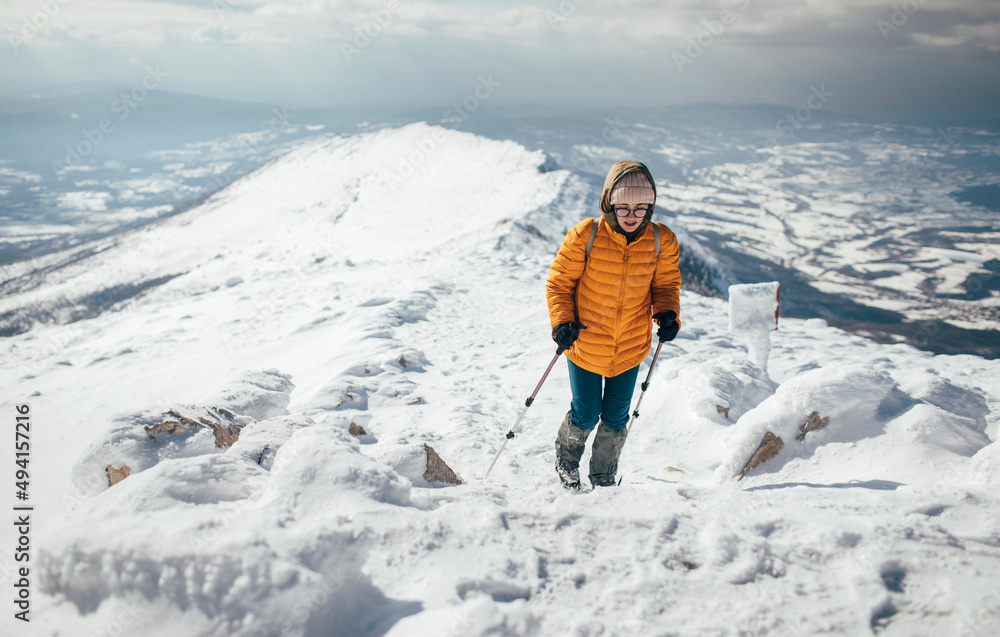 Young woman climbing on the snowy mountain ridge