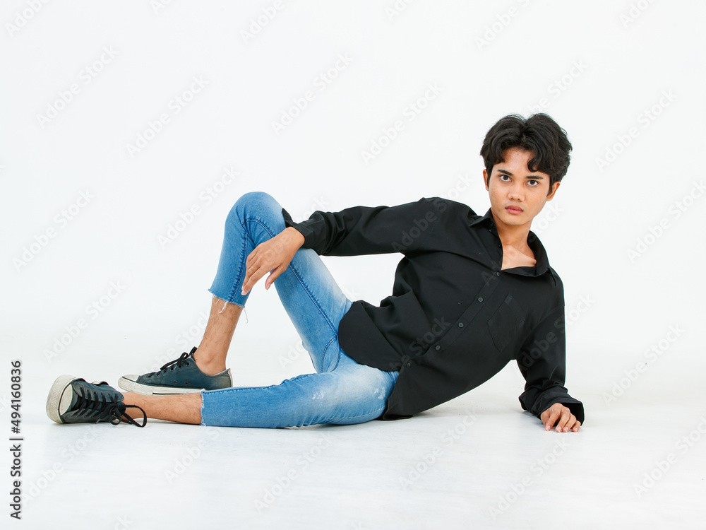 Portrait isolated cutout studio shot of Asian young LGBTQ gay glamour male model in casual black shirt and jeans outfit sitting stretching posing gesturing on floor look at camera on white background Portrait isolated cutout studio shot of Asian young LGBTQ gay glamour male model in casual black shirt and jeans outfit sitting stretching posing gesturing on floor look at camera on white background