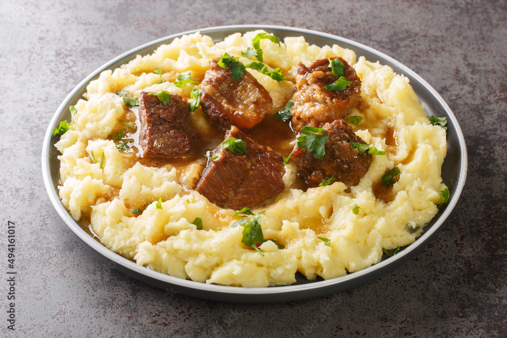 Greek Sofrito Slow braised beef with spicy gravy garnished with mashed potatoes close-up in a plate on the table. horizontal Greek Sofrito Slow braised beef with spicy gravy garnished with mashed potatoes close-up in a plate on the table. horizontal