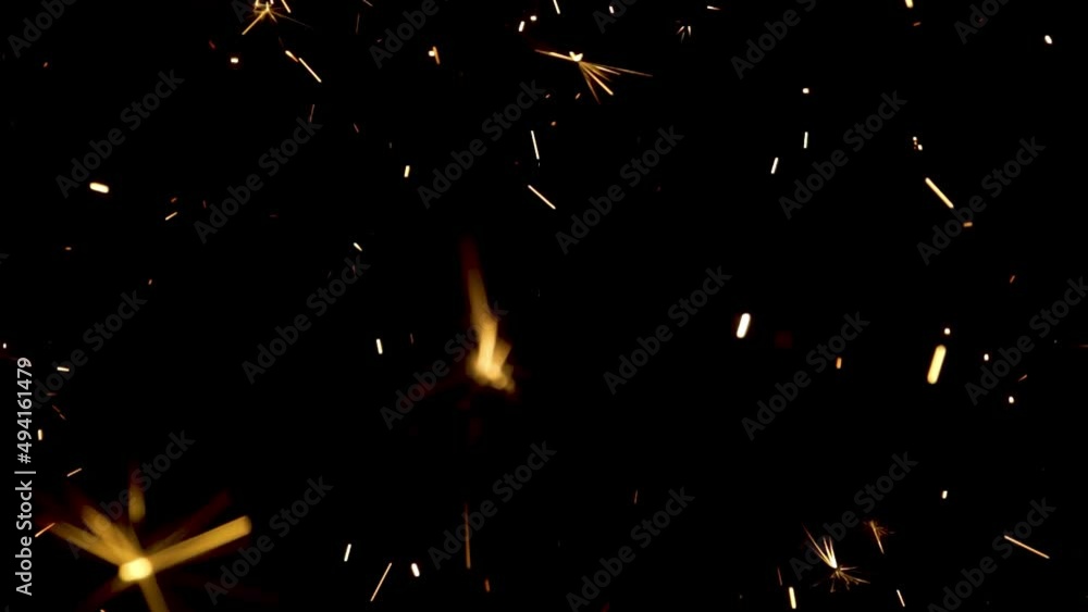 Sparkling splashes of bengal fires on black background. Lightening shine particles sparkler in dark. Sparkling bengali firework with golden splashes of sparks. Concept holiday. Close up. Slow motion. Sparkling splashes of bengal fires on black background. Lightening shine particles sparkler in dark. Sparkling bengali firework with golden splashes of sparks. Concept holiday. Close up. Slow motion.
