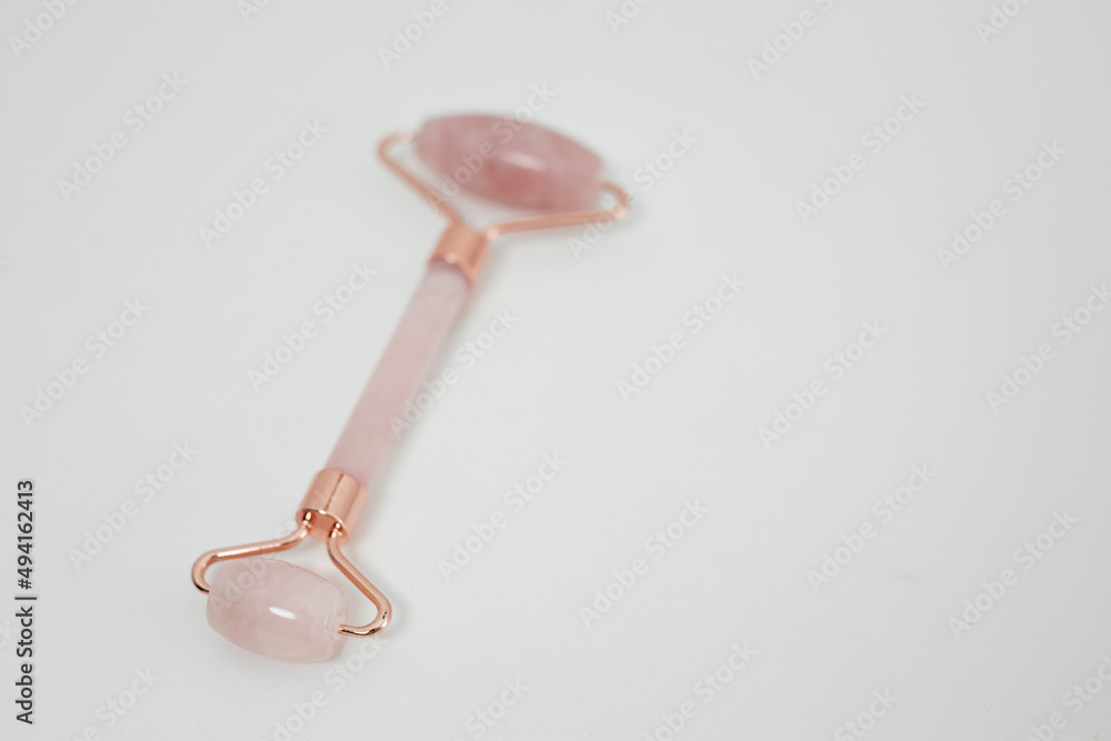 Rose quartz facial roller isolated on white background. Skin care concept Rose quartz facial roller isolated on white background. Skin care concept