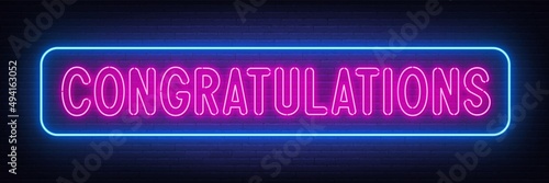 Neon lettering congratulations on brick wall background.