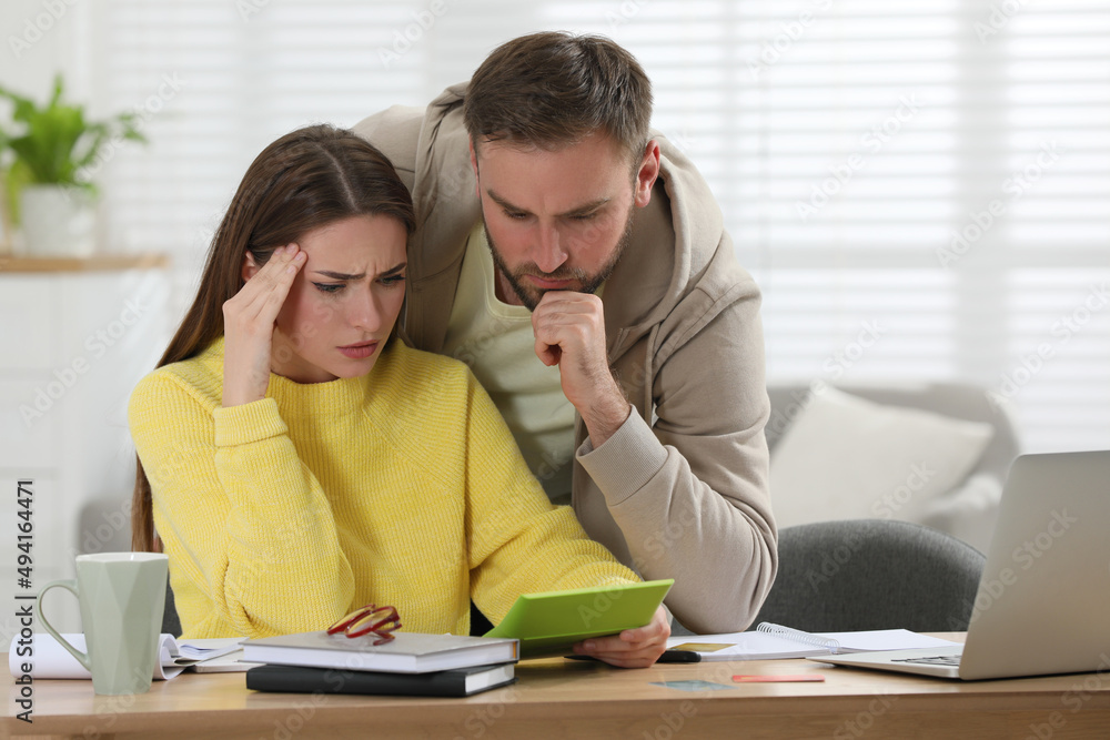 Young couple discussing family budget at table in living room Young couple discussing family budget at table in living room