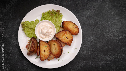 Homemade fried potatoes with sauce, on a dark background