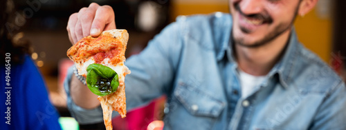 Foto Horizontal banner or header Close-up hipster young male sitting at table eating and laughing because his piece of pizza has too much stringy mozzarella cheese