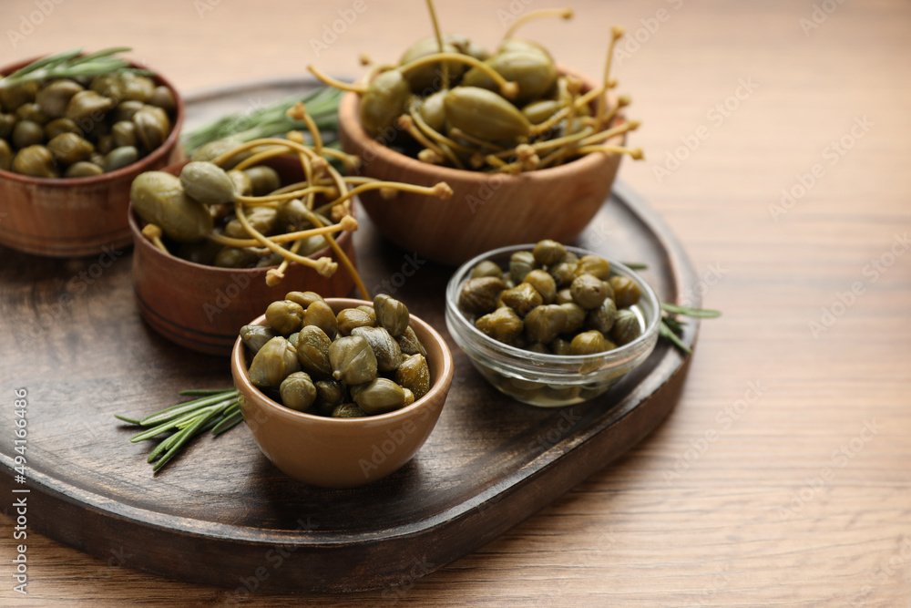 Delicious pickled capers and rosemary twigs on wooden table Delicious pickled capers and rosemary twigs on wooden table