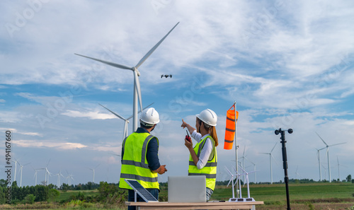 Engineers using meteorological and drone instrument collect data laptop to measure the wind speed, temperature,humidity and solar cell system on wind turbine station is sustainable energy concept.