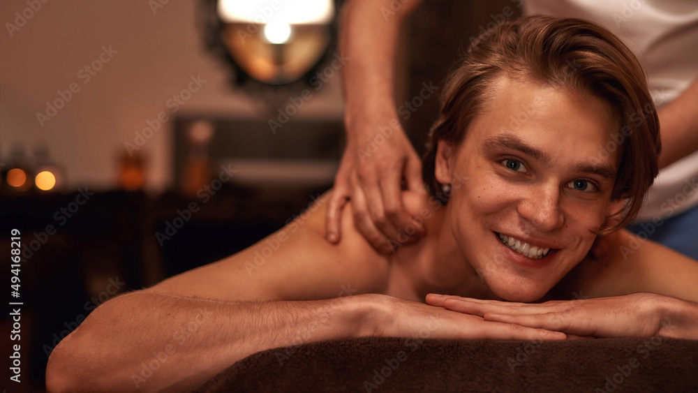Masseur doing back massage of relaxing male client Masseur doing back massage of relaxing male client
