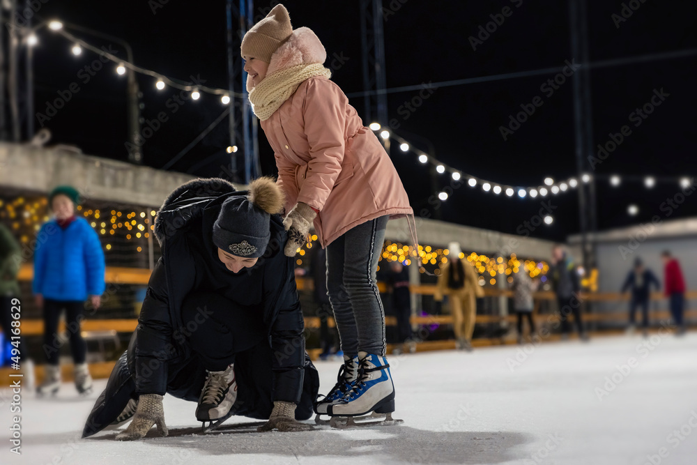 Fototapeta premium mother and daughter are skating, mother has fallen and is trying to get up