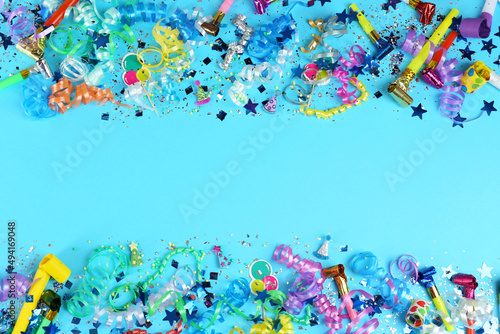 Colorful serpentine streamers, confetti and party horns on light blue background, flat lay. Space for text