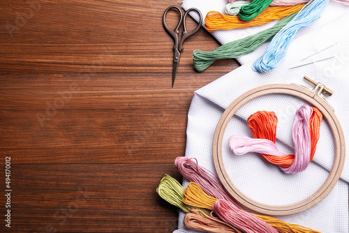 Foto Set of embroidery equipment on wooden table, flat lay