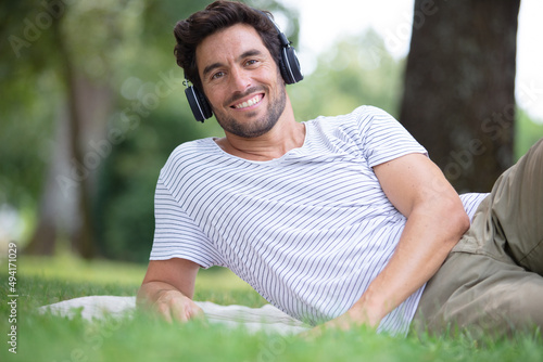 relaxed male listening to music while lying in a park