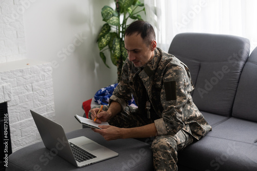 patriotic military man in headset looking at laptop near american flag