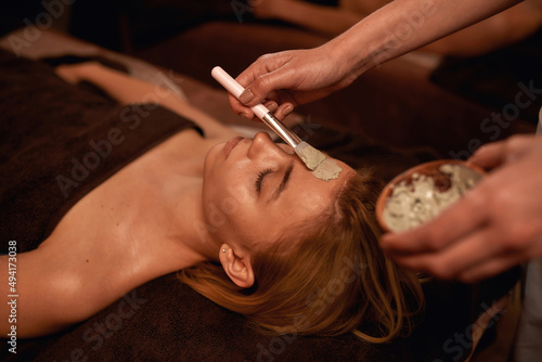 Photos Cosmetician applying clay mask on face of woman