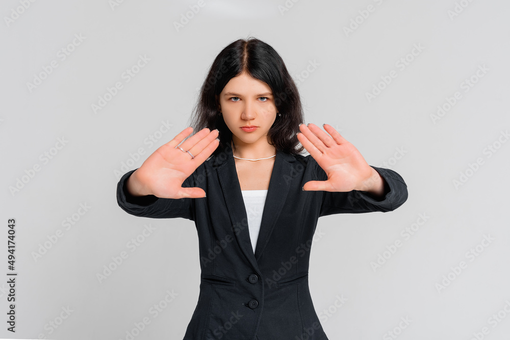 Please, do not, stop. Young serious dark-haired girl, who is looking in the camera and extends palms in stop sign, standing over gray background. Stay home. Social distancing. New normal behavior Please, do not, stop. Young serious dark-haired girl, who is looking in the camera and extends palms in stop sign, standing over gray background. Stay home. Social distancing. New normal behavior