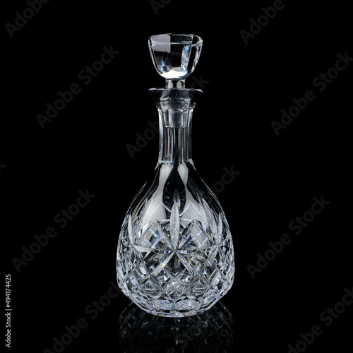 antique glass decanter with geometric pattern. retro decanter for alcohol on a black isolated background. engraved vintage decanter