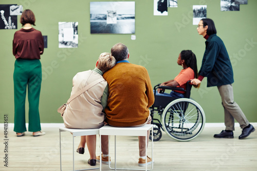 Group of diverse senior and young people spending free time in modern art gallery looking at abstract photos and relaxing photo