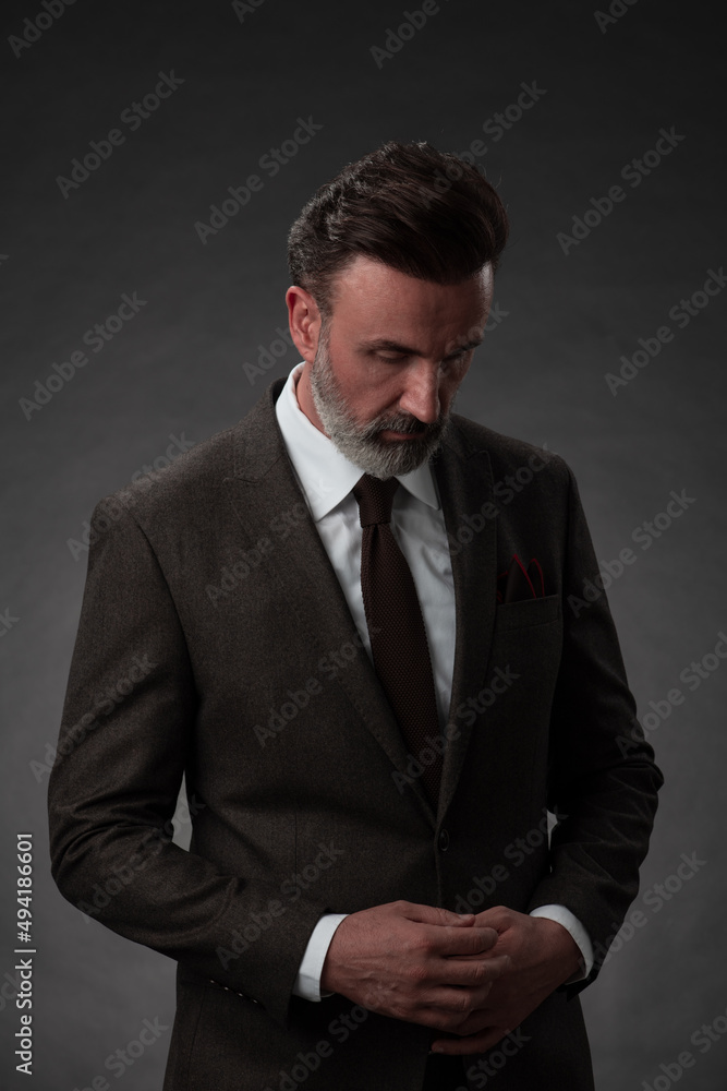 Portrait of a stylish elegant senior businessman with a beard and casual business clothes in photo studio isolated on dark background gesturing with hands Portrait of a stylish elegant senior businessman with a beard and casual business clothes in photo studio isolated on dark background gesturing with hands