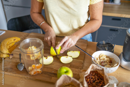 Young woman cutting fresh apple on wooden table