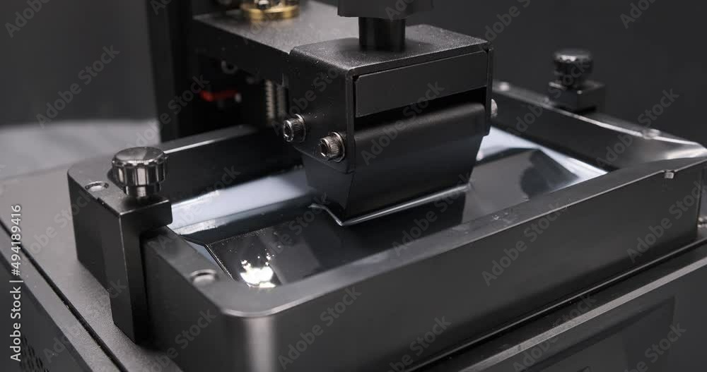 Close up shot of Resin MSLA 3D Printer build platfrom moving up and down in the resin vat during 3d printing. MSLA 3D printing. Additive manufacturing Close up shot of Resin MSLA 3D Printer build platfrom moving up and down in the resin vat during 3d printing. MSLA 3D printing. Additive manufacturing
