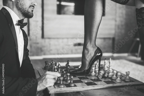 Fotografia Sexy woman leg in stockings and high heels steps into chess board black and whit